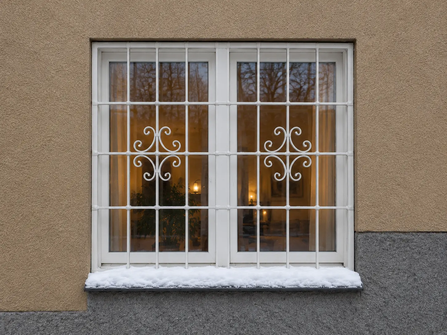 Vitt fönstergaller med smidda ornament på putsad fasad i Stockholm