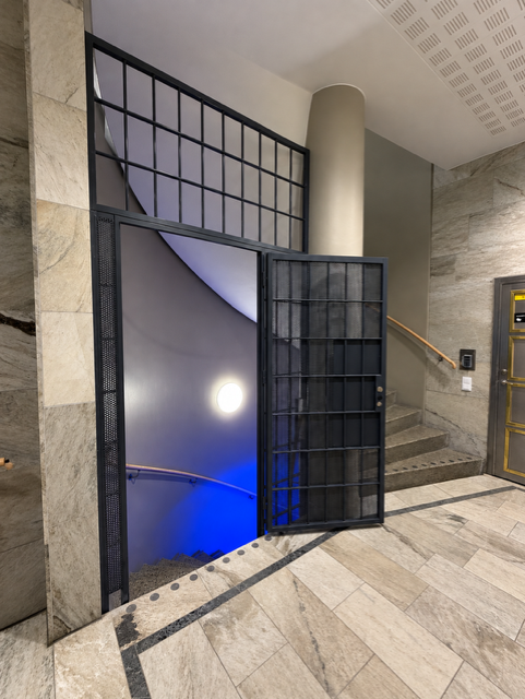 Lackerad gallergrind framför lägenhetsdörr i Stockholm