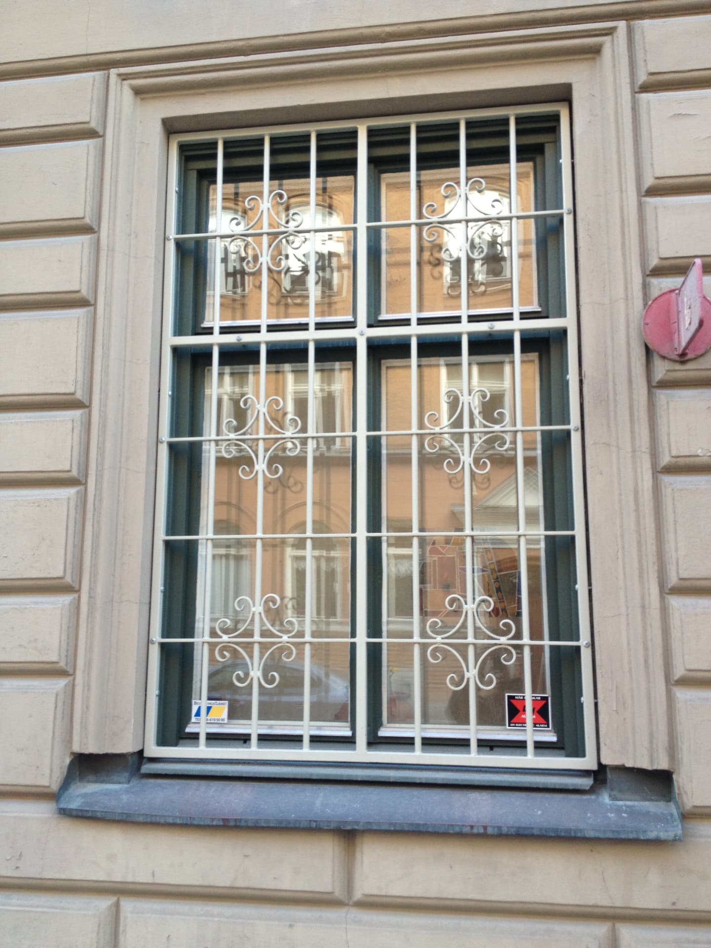 Vitt dekorativt fönstergaller med smidda spiraler på stenfasad i Stockholm